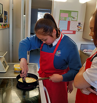 Queen's High School Technologies - girls trying their hand at making an omelette in technology class